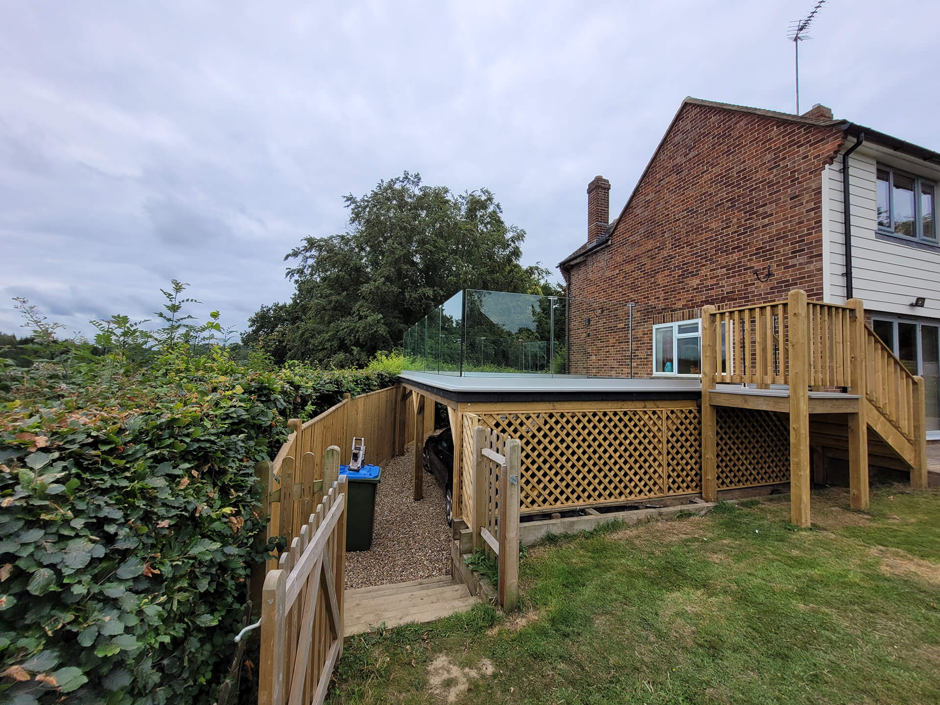 Raised decking and retaining wall construction by Deerwood Construction in Crowborough East Sussex with timber fencing and glass balustrade.